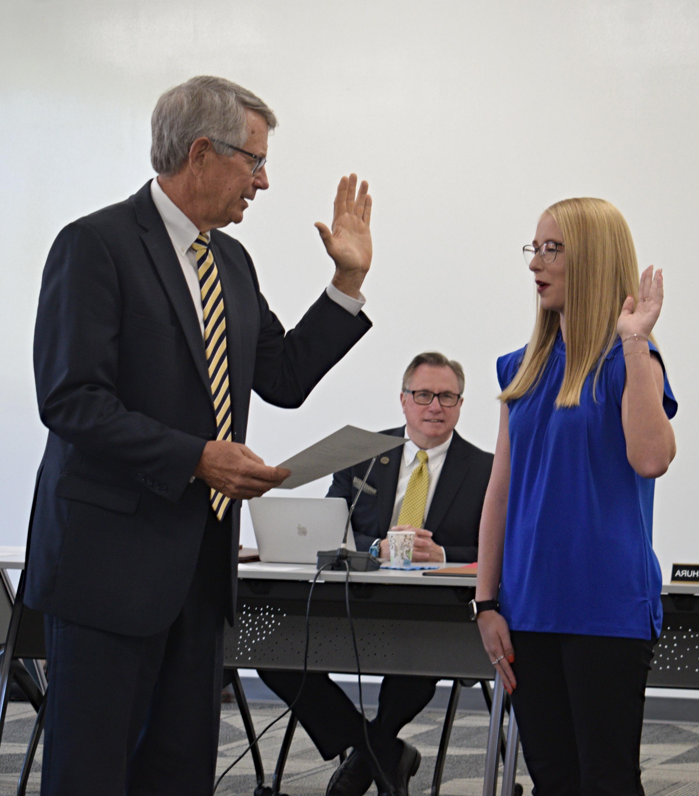 学生受托人盖尔·鲍在大学律师布伦特·斯塔基的陪同下宣誓就职时举起了手.